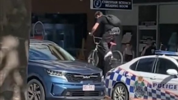 Footage of an individual riding a bike over a police car during a riot that erupted in Brisbane’s CBD on the weekend.