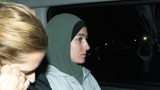 Janai Safar is escorted from the airport to the police station.