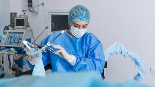 A nurse prepares a medical instrument for performing a hysteroscopy operation.