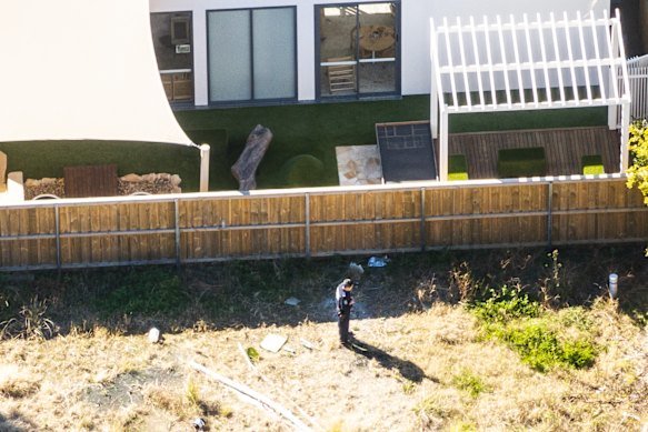 A forensic officer gathering evidence at a vacant block behind Play to Learn Castle Hill following a fire in July.
