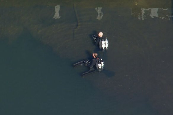 Police divers in the Hacking River after a fatal crash in the Royal National Park.