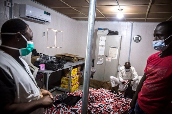 Medics from Médecins Sans Frontières stand over a pile of therapeutic food Plumpy’Nut, which is meant to treat malnourishment, in Maiduguri, Nigeria.