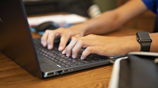 A high school student works on an assignment on a laptop.