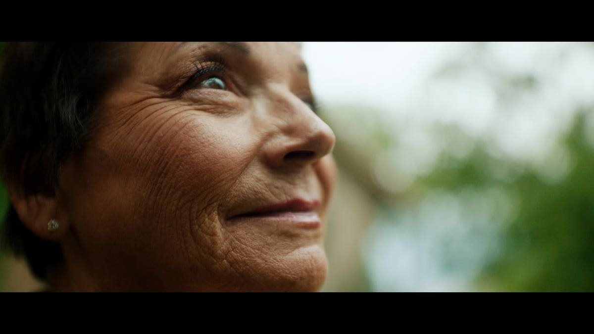 A close-up screenshot of Deb Proctor smiling away from the camera.