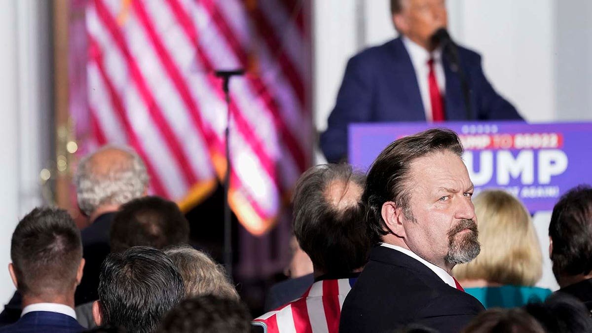 Sebastian Gorka looking behind former President Donald Trump speaking to supporters at Trump National Golf Club Bedminster