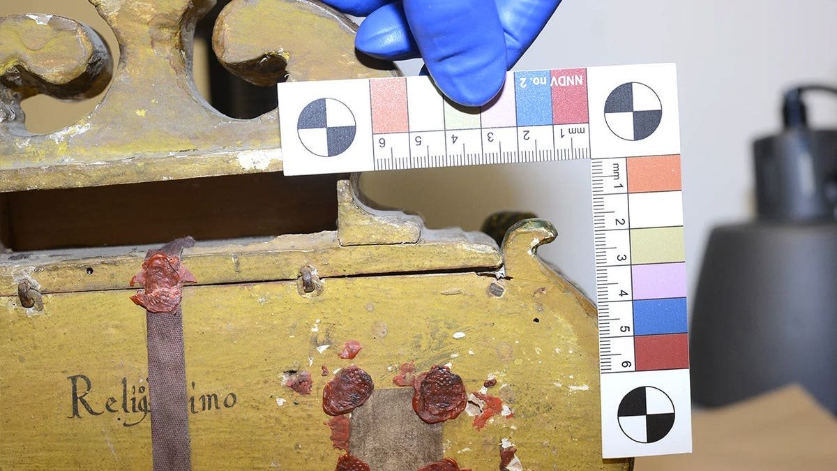 FBI agent measuring gilded Catholic urn