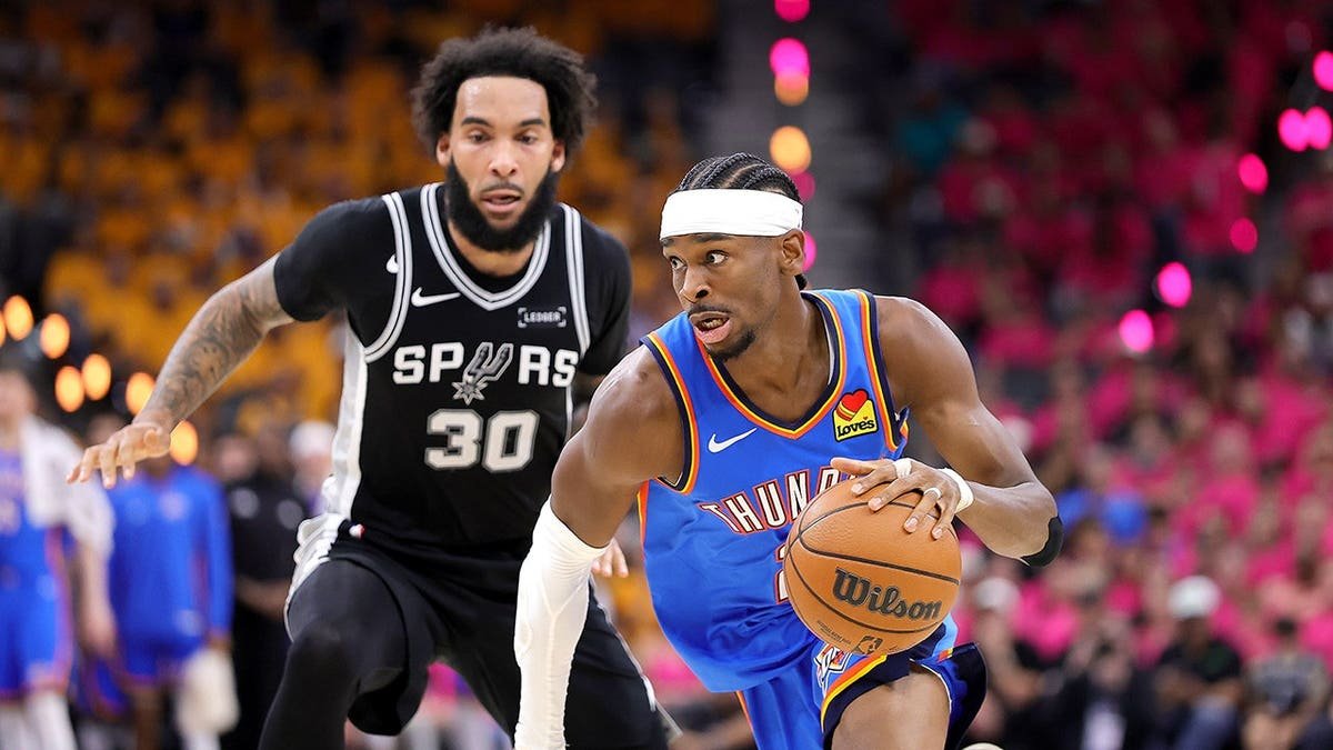 Shai Gilgeous-Alexander driving to basket past Julian Champagnie in basketball game
