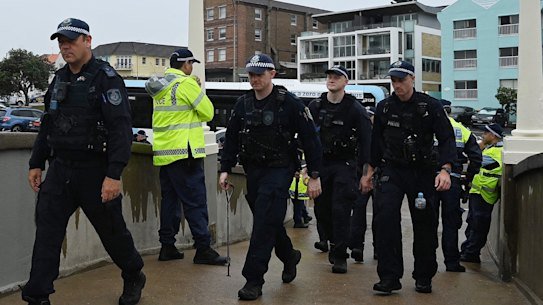 NSW Police walk toward Bondi Beach in February, three months after gunmen opened fire into a crowd of Jewish families from the footbridge.