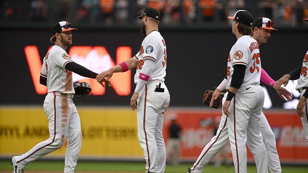 Baltimore Orioles players Taylor Ward, Shane Baz, Adley Rutschman and Dylan Beavers high-fiving on field
