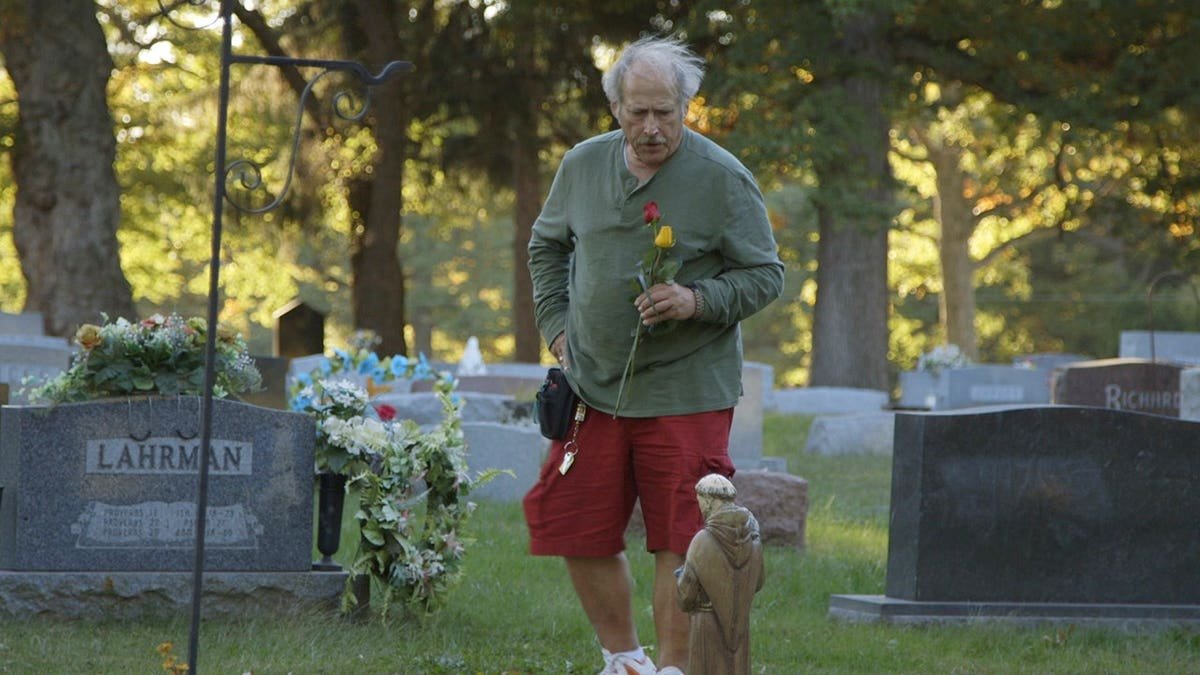 Benjaman placing a rose at his brother's grave.