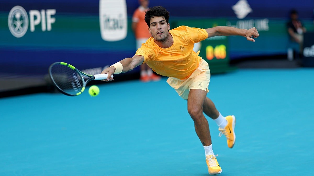 Carlos Alcaraz reaching for a forehand during a tennis match at Hard Rock Stadium