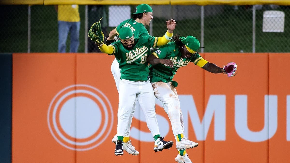 Athletics left fielder Carlos Cortes celebrating with teammates Zack Gelof and Lawrence Butler on baseball field