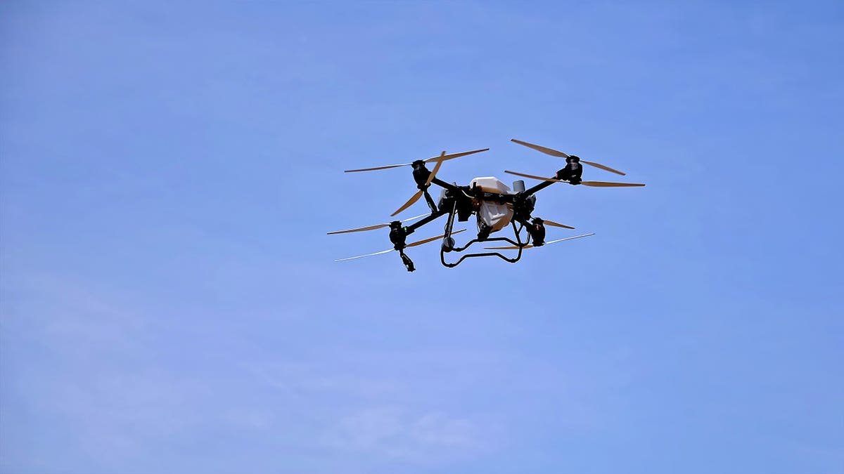 A drone flying in the sky carrying a payload