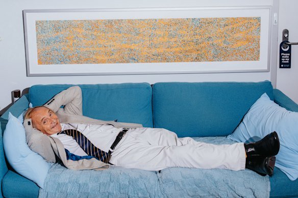 Professor Alex McBratney in his office, on the coach he naps on,with one of his artworks above.