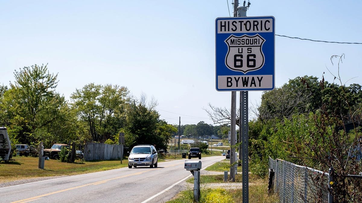 Historic Missouri US 66 Byway road sign along rural two-lane highway with car and trees