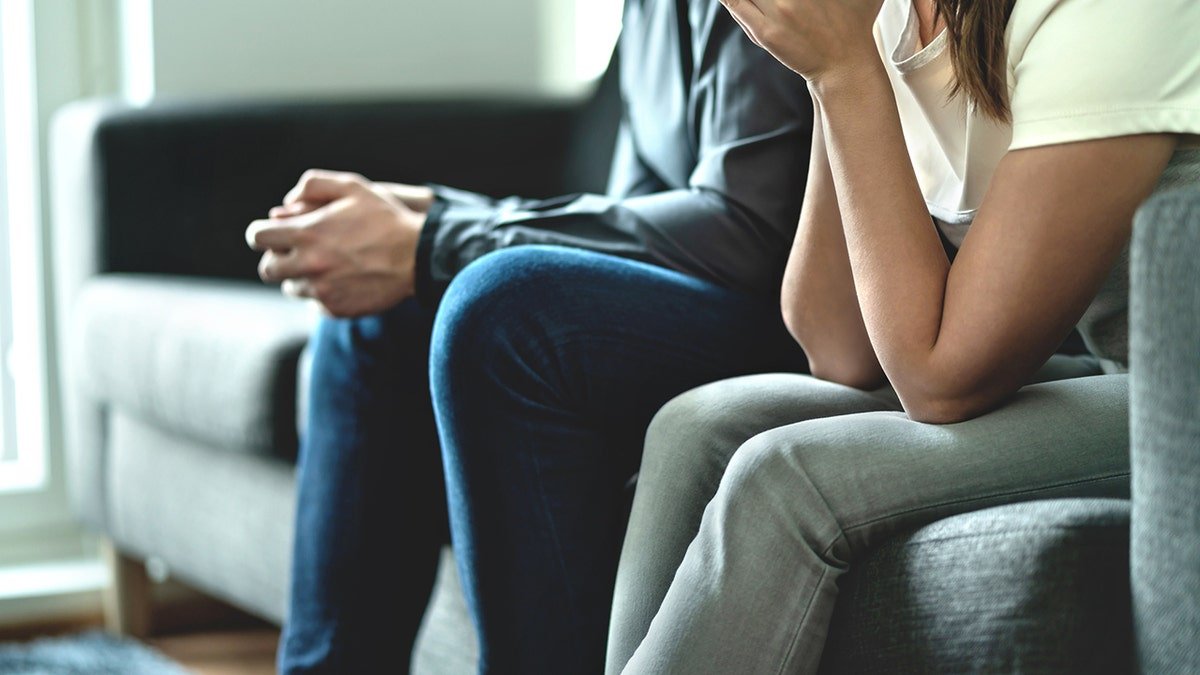 Sad upset married man and woman sitting together showing no trust
