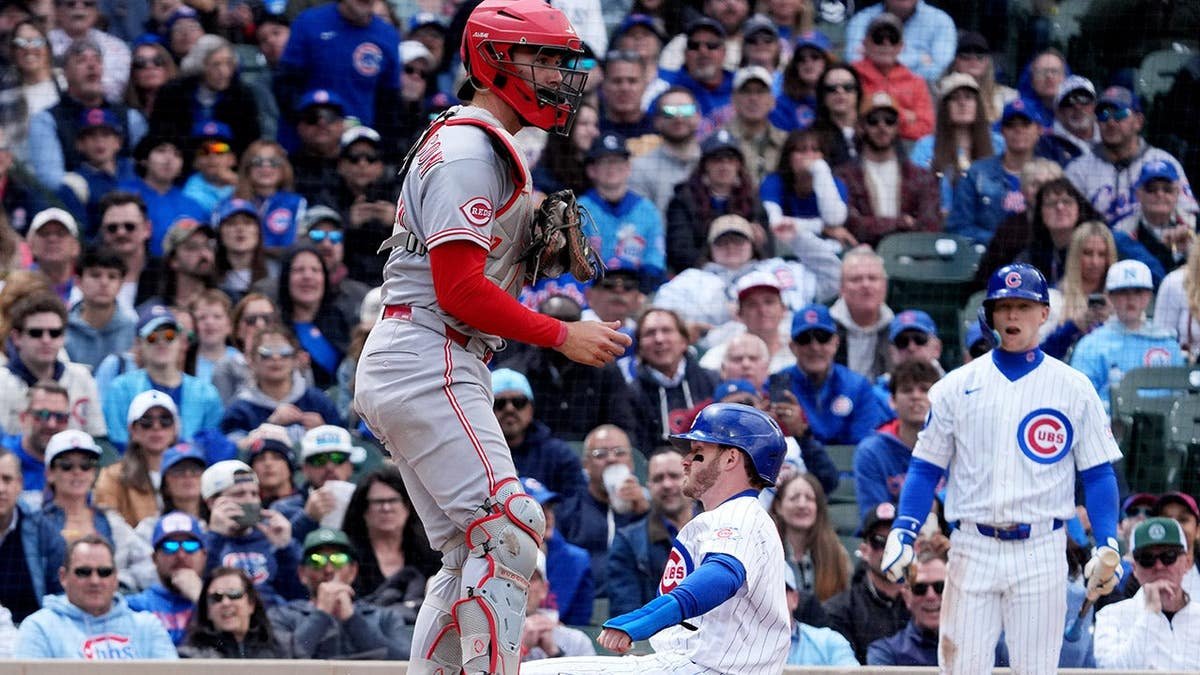 Chicago Cubs left fielder Ian Happ safe at home plate with Cincinnati Reds catcher Tyler Stephenson nearby at Wrigley Field