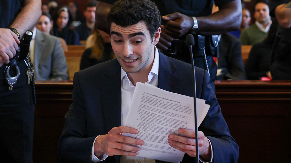 Luigi Mangione holding papers at defense table in Manhattan courtroom