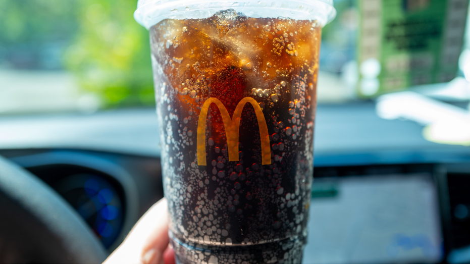 A person is seen holding a McDonald's soda.