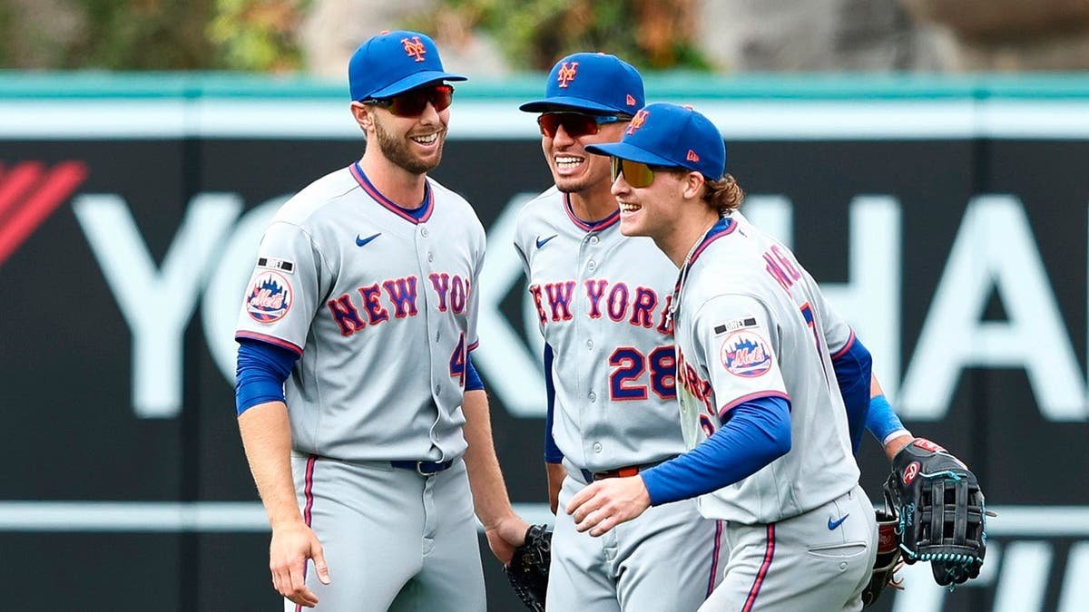 New York Mets players Austin Slater, Tyrone Taylor, and Carson Benge celebrating on the field.