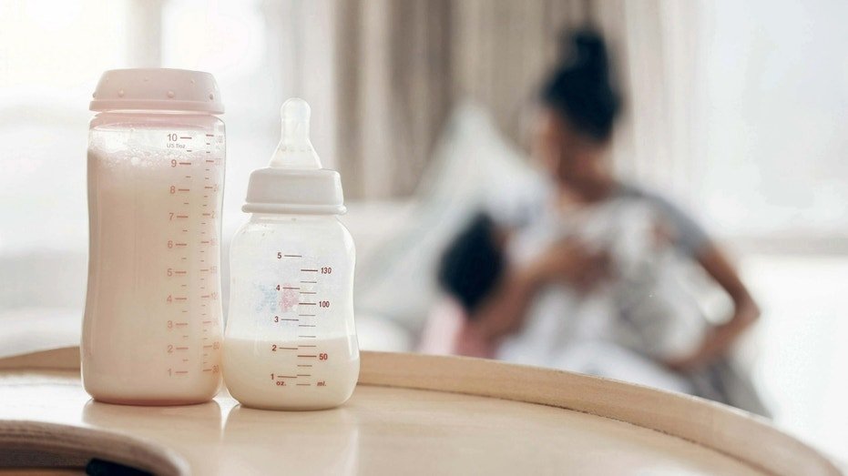 Baby formula with a mother and child in background.