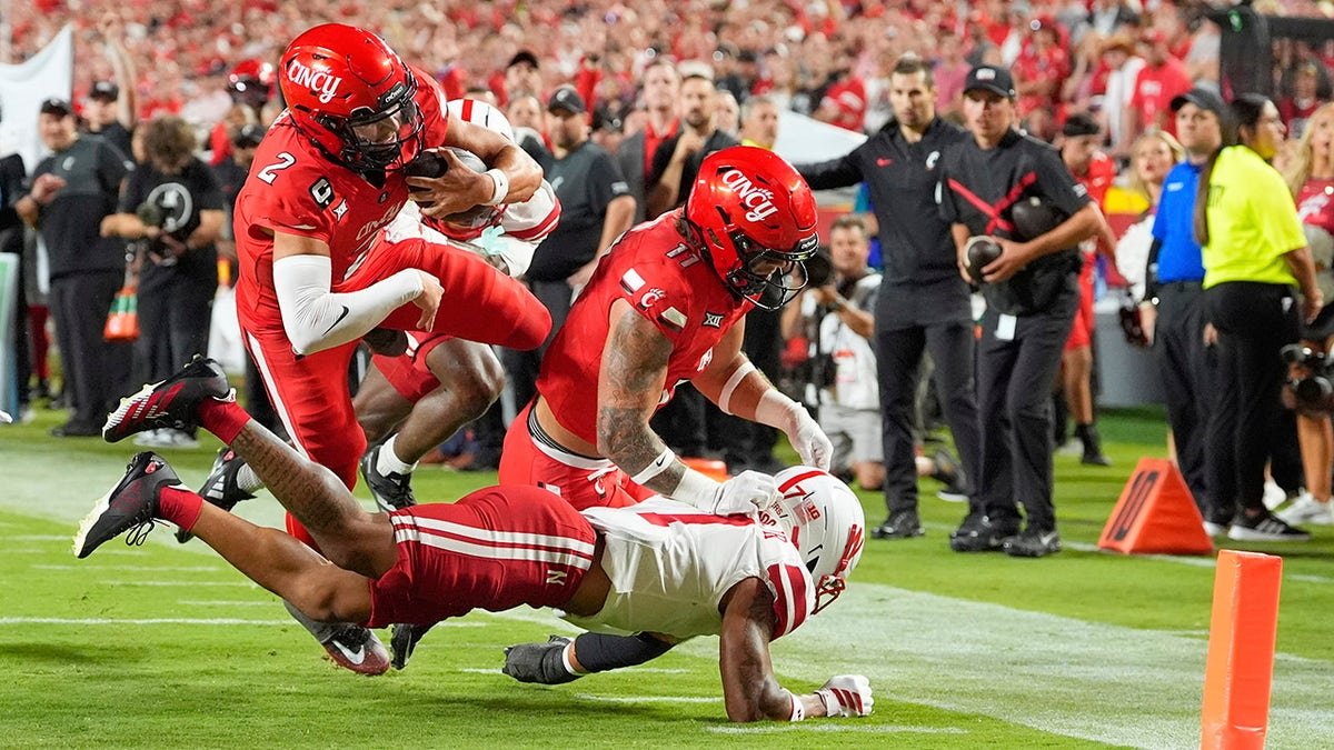 Cincinnati quarterback Brendan Sorsby leaps over Nebraska defensive back Malcolm Hartzog Jr. to score a touchdown.