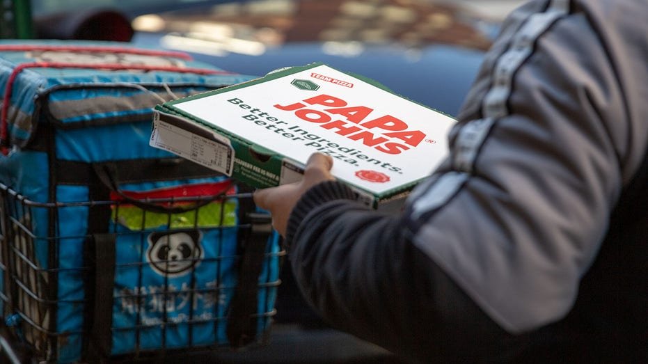 A delivery person carrying Papa Johns pizza box.