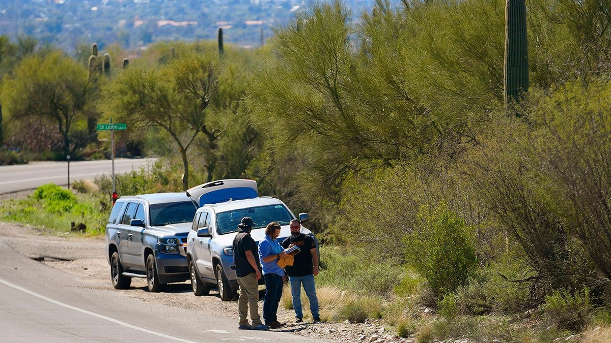 Law enforcement personnel looking near a roadway outside Nancy Guthrie's neighborhood in Catalina Foothills Tucson