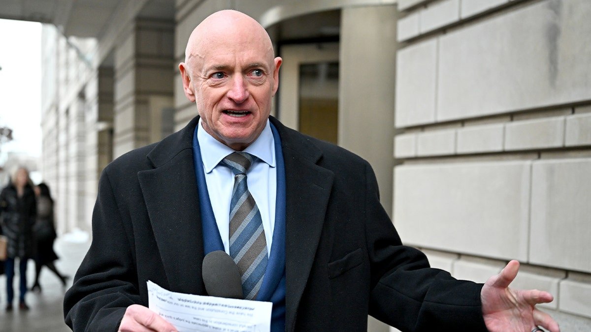 Mark Kelly addresses reporters while standing outdoors near a courthouse.