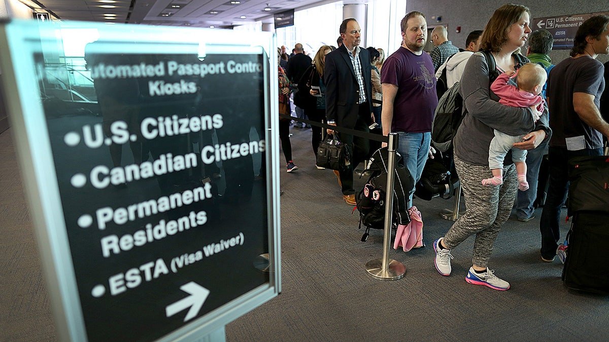 Passengers waiting in line to use Automated Passport Control Kiosks at Miami International Airport