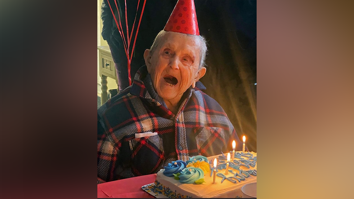 Undated photo shows WWII Navy veteran John Bernard Arnold III celebrating a birthday while wearing a party hat and sitting beside a birthday cake.