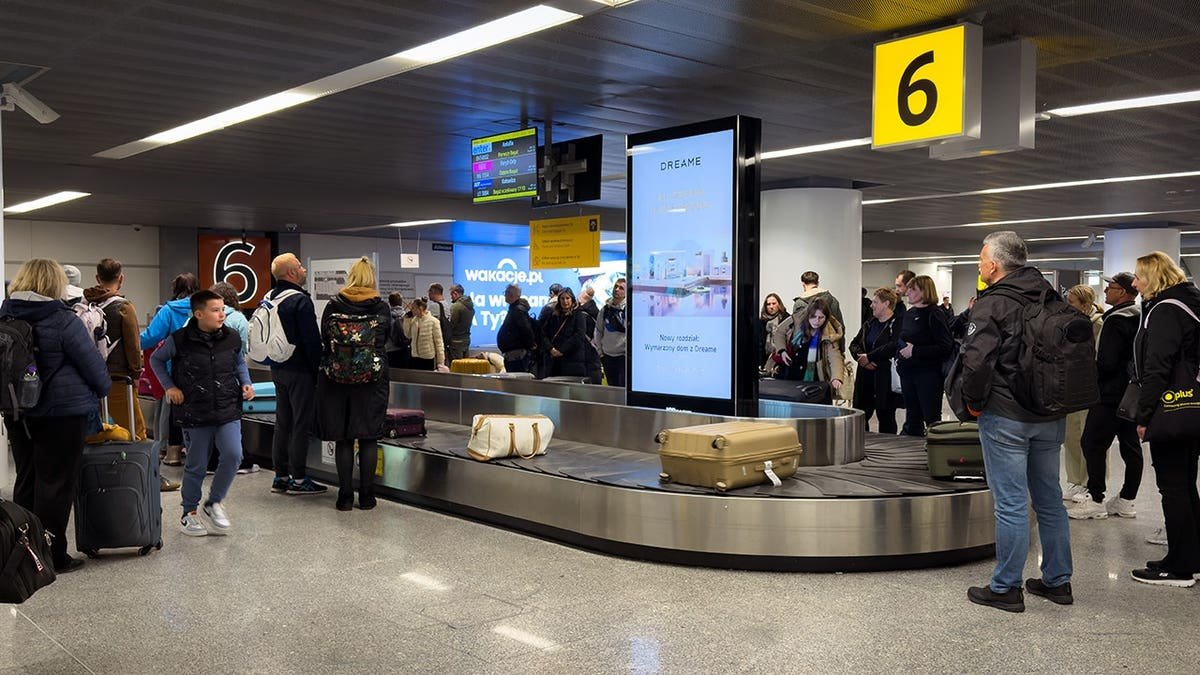 Passengers waiting for luggage at a baggage carousel in Warsaw Chopin Airport