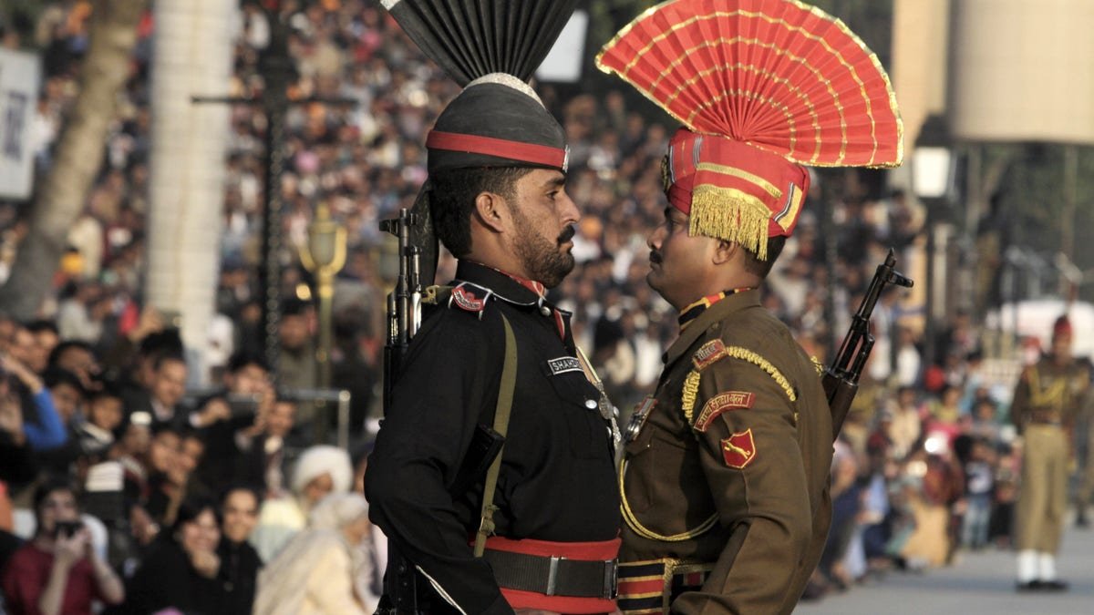 FILE -- In this Friday, Jan. 11, 2013 file photo, a Pakistani Ranger in black uniform and his Indian counterpart, march during a flag off ceremony, at the joint Pakistan-India border check post of Wagah near Lahore, Pakistan. Despite the worst violence in a nearly a decade along the disputed Kashmir border, tension has not spiraled out of control between Pakistan and India, showing just how far the archenemies have come since relations were shattered by the 2008 Mumbai terror attack. (AP Photo/K.M. Chaudary, File)