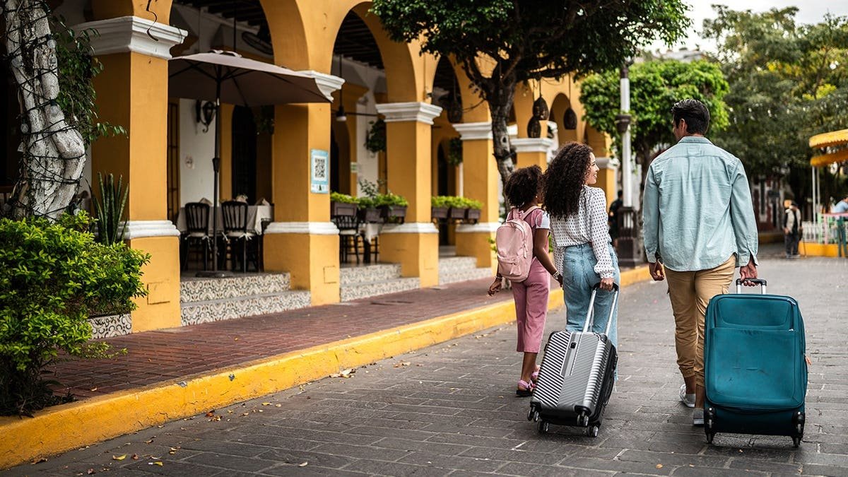 Tourist family walking with luggage in a historic district