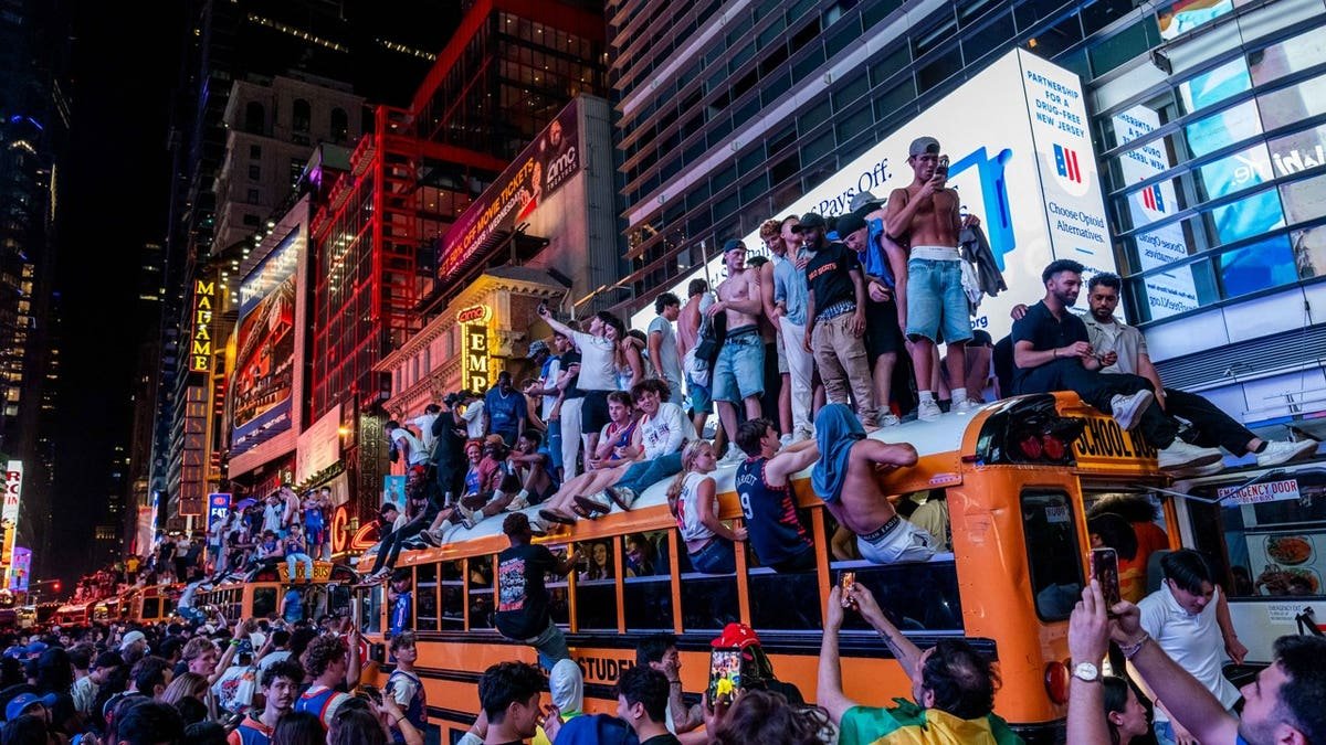 New York Knicks fans climb on buses as they celebrate after they win the NBA Finals in Times Square on June 14, 2026 in New York City.