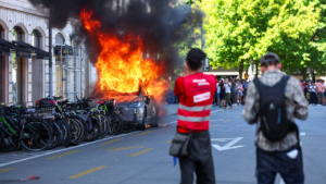 Anti-G7 protest turns violent as demonstrators torch Tesla and smash UN office windows Anti-G7 protest turns violent as demonstrators torch Tesla and smash UN office windows