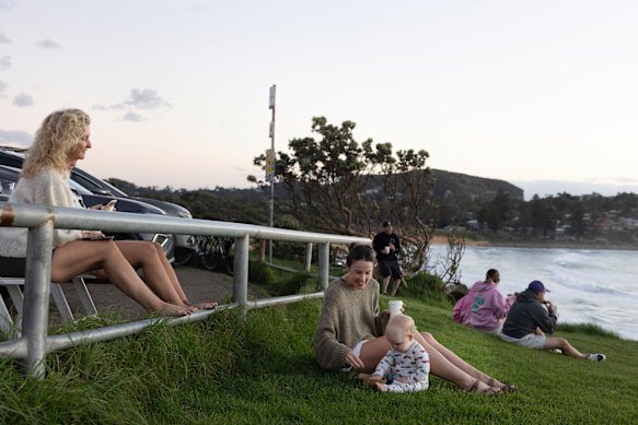 People enjoy the sunrise from the southern headland at Avalon.