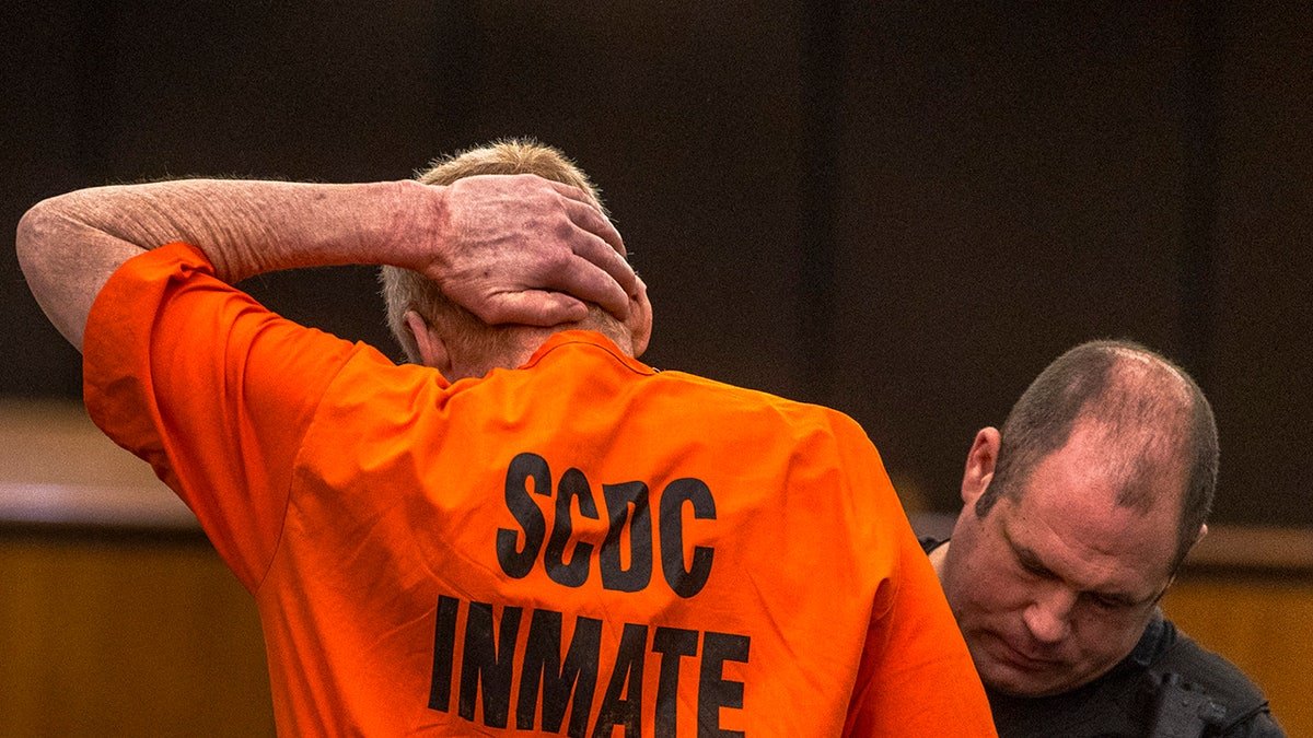 Alex Murdaugh touching the back of his head during a hearing in a courtroom.