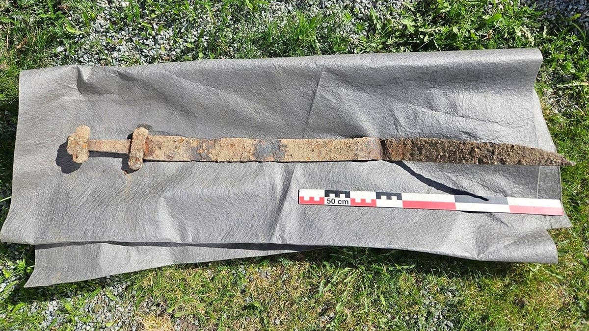 Rust-covered sword lying on protective mat in field