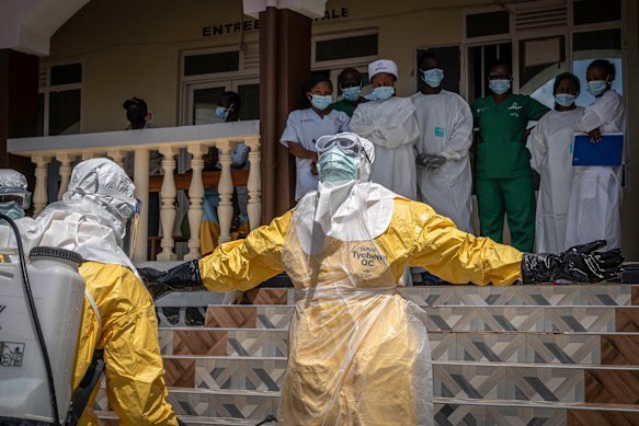 Health workers are sprayed with disinfectant after coming into contact with the body of a person suspected of having died from Ebola in Bunia, in the eastern Democratic Republic of the Congo.