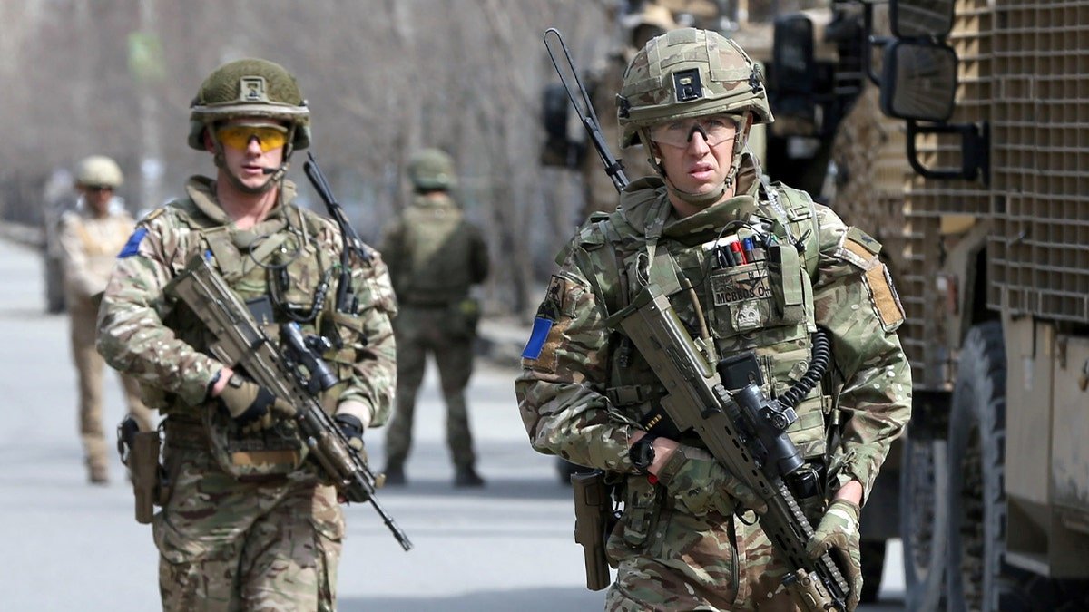 British soldiers in military gear move through a secured area following an attack.