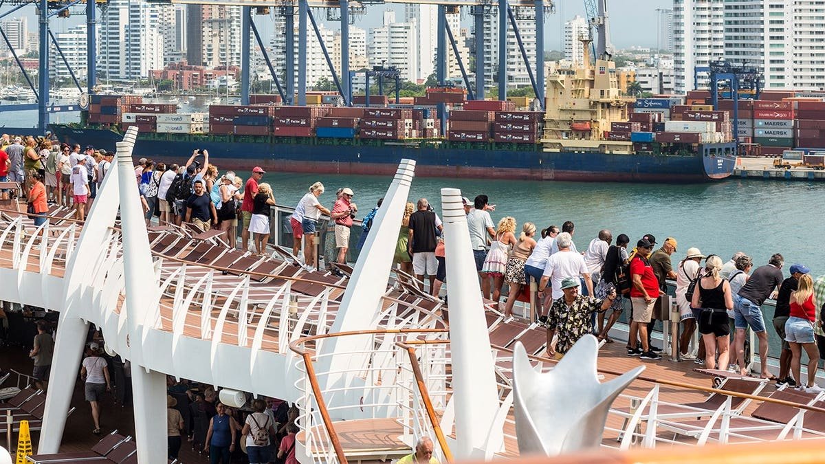 Passengers aboard a cruise ship admiring Cartagena cityscape with container port in foreground