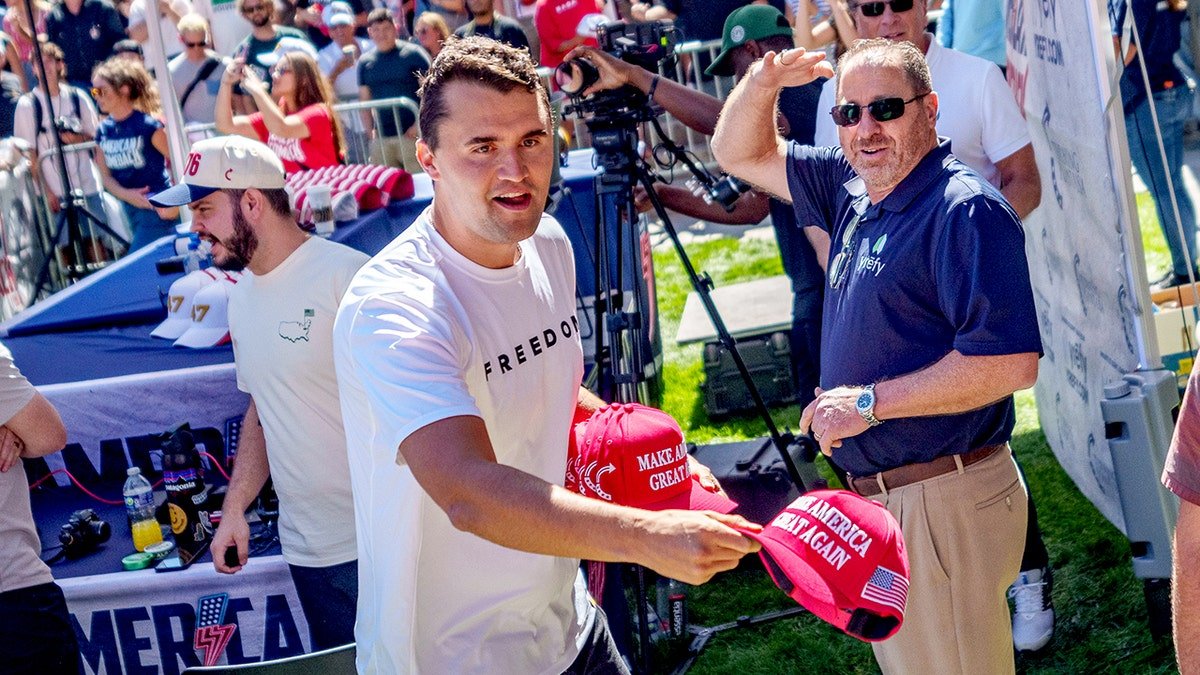 Charlie Kirk throwing a Make America Great Again hat to a crowd at Utah Valley University