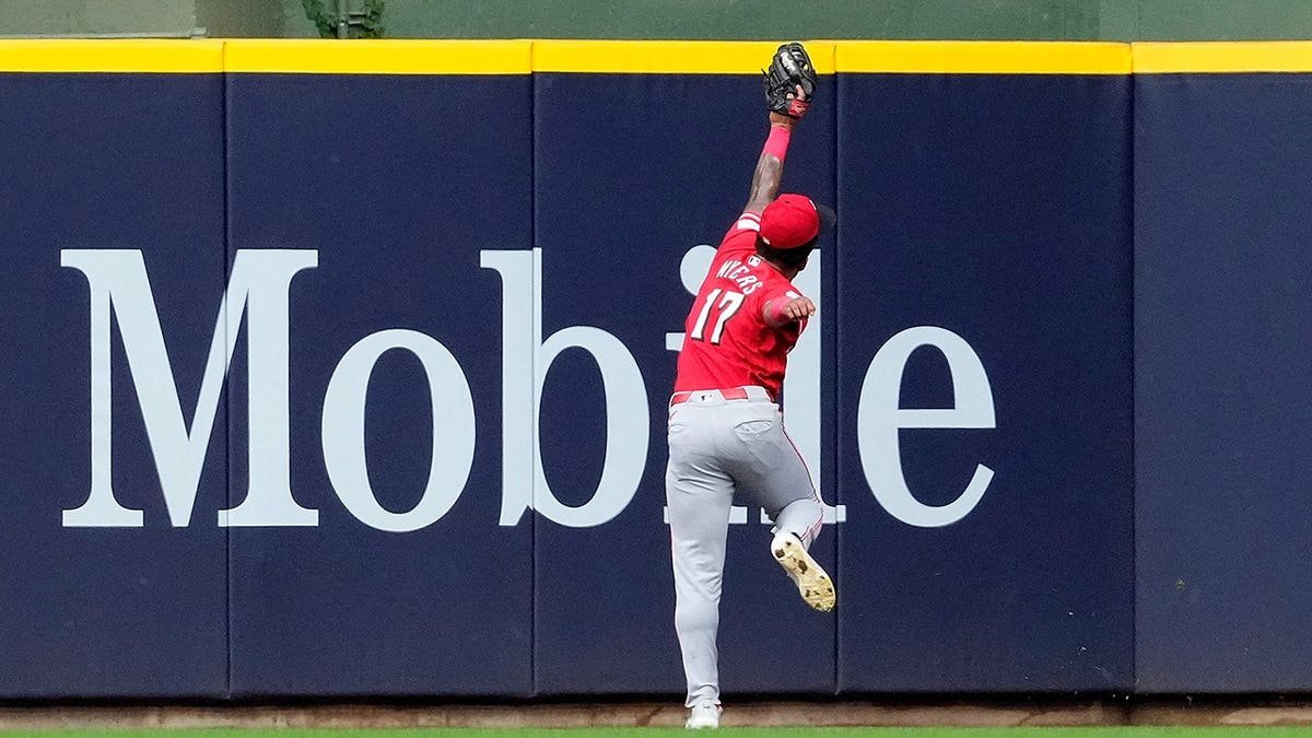 Dane Myers of the Cincinnati Reds making a running catch near the wall at American Family Field.