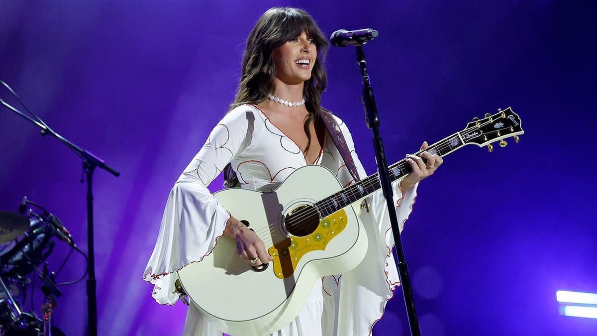 Ella Langley holds a guitar on stage.