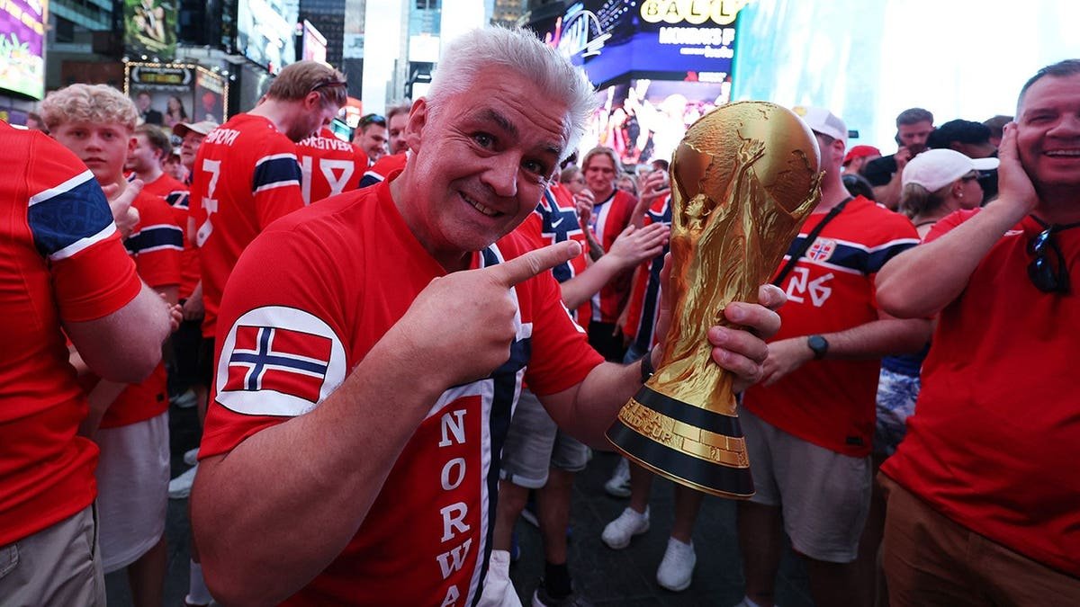 A Norway fan holding a replica FIFA World Cup trophy in Times Square New York