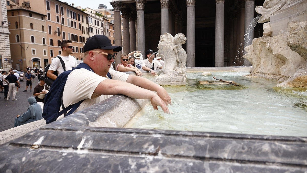 Man dips his hands in a Roman fountain