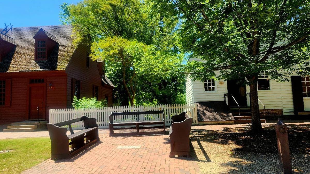 Wooden benches face each other on a street in Colonial Williamsburg.