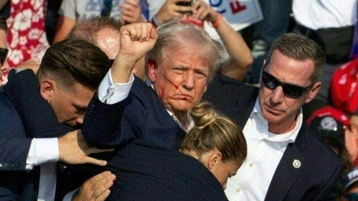 Republican candidate Donald Trump with blood on face surrounded by Secret Service agents on stage