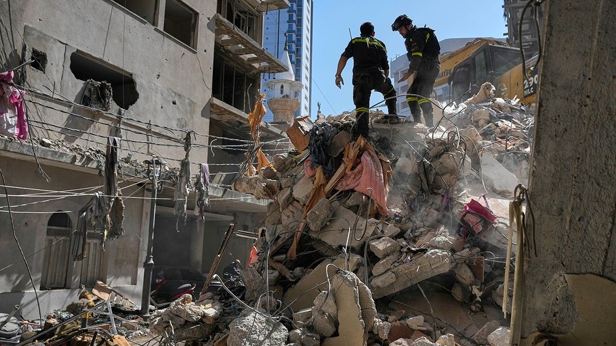Lebanese civil defense workers inspecting rubble at a destroyed building site in Beirut